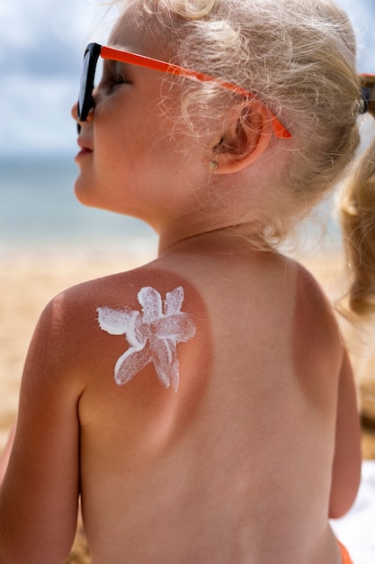 Free Photo view of young girl at the beach with lotion on sunburn skin