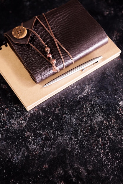 Free photo vintage aged notebook on a diary next to a pencil on a dark board