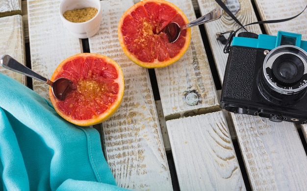 Vintage camera and napkin with halved grapefruit on wooden backdrop