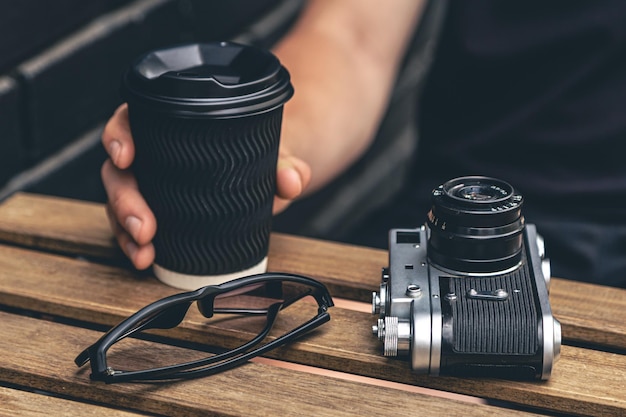 Free photo vintage film camera and a glass of coffee on a wooden table