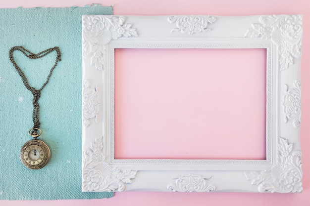 Vintage photo frame near blue paper and old pocket watch 