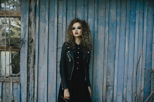 Vintage woman as witch, posing against the backdrop of an abandoned place on the eve of Halloween