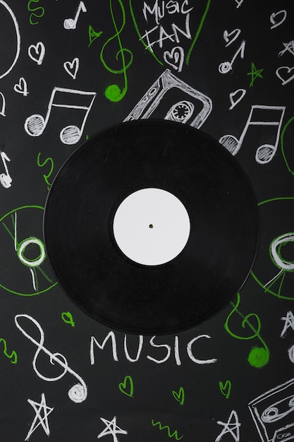 Vinyl record over the blackboard with drawn musical notes