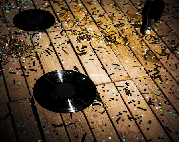 Free photo vinyl records and bottle of drink between confetti