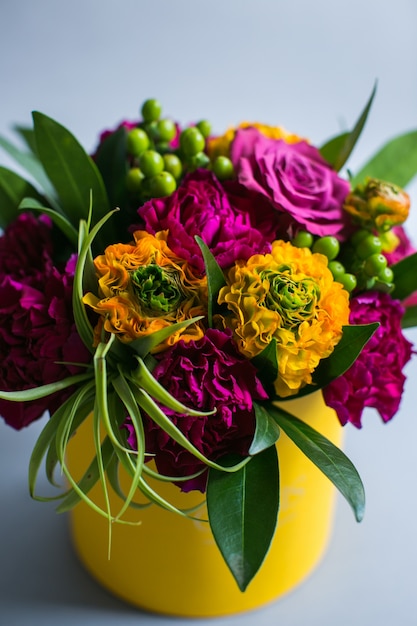 Free photo violet and yellow flowers put in a paper box stand on grey background