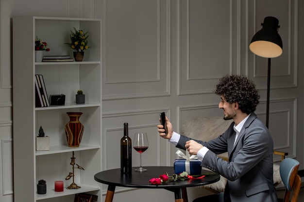 Virtual love handsome cute guy in suit with wine on a distance phone date holding phone