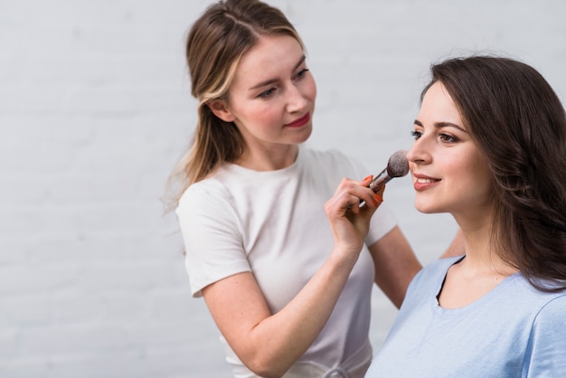 Visagiste covering face of model with powder 