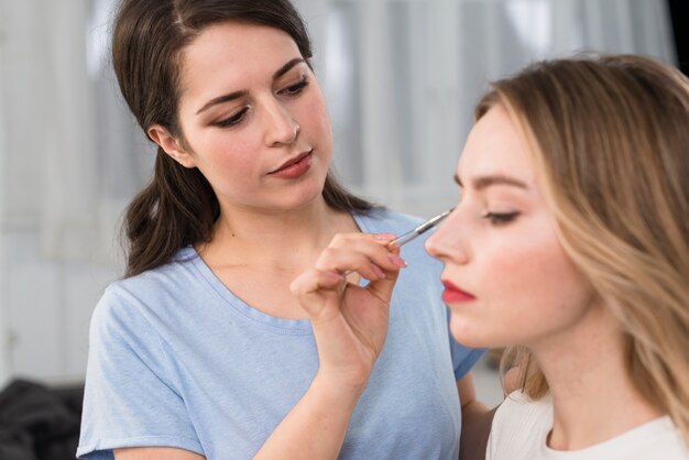 Visagiste doing makeup of eyes for client