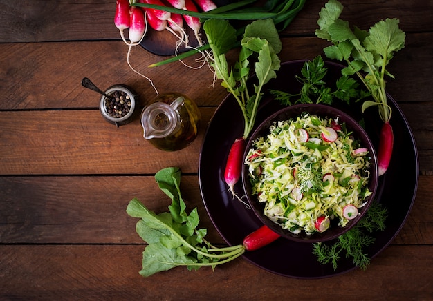 Free photo vitamin salad of young vegetables: cabbage, radish, cucumber and fresh herbs. top view