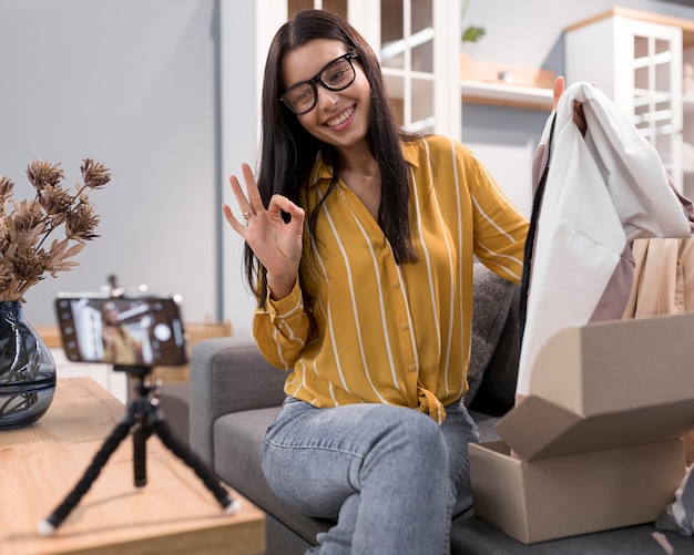 Vlogger at home unboxing clothes with smartphone