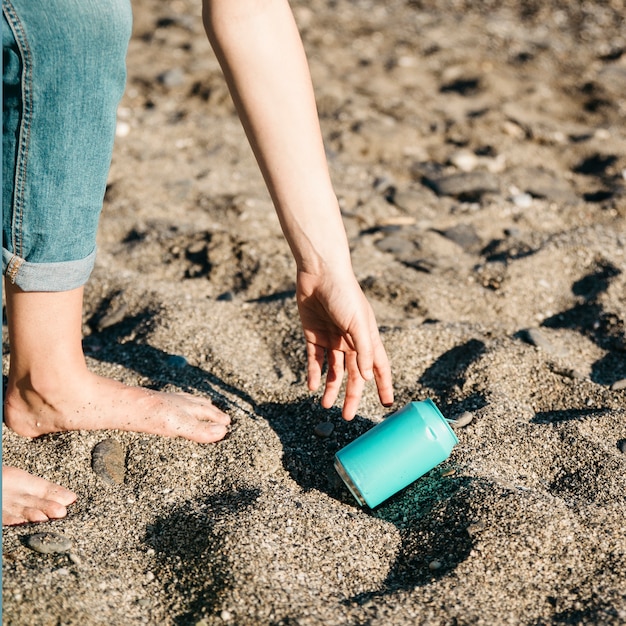 Free photo volunteer collecting can at the beach