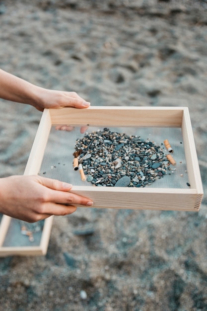 Free photo volunteer collecting cigarettes at the beach