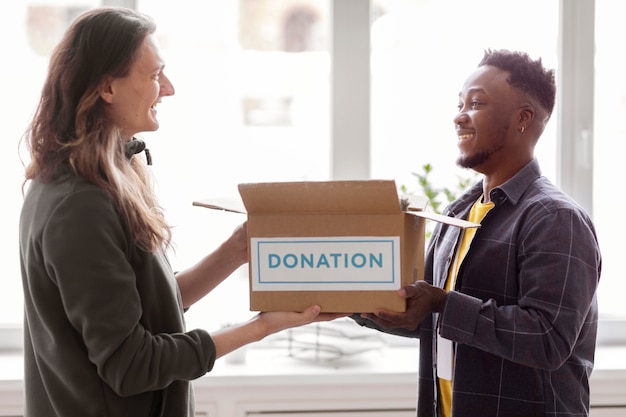 Free photo volunteer collecting a donation box from another volunteer