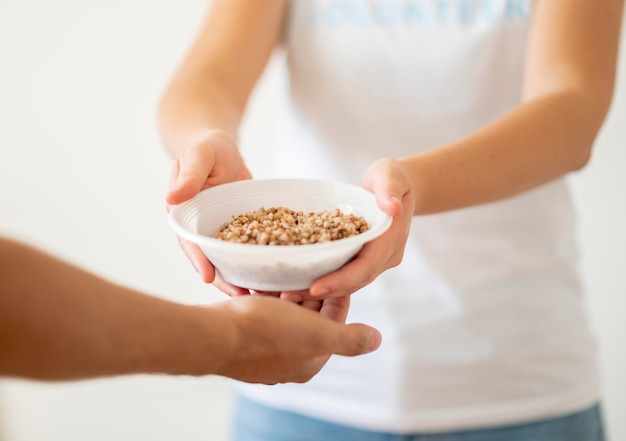 Volunteer handing bowl of donated food to needy person