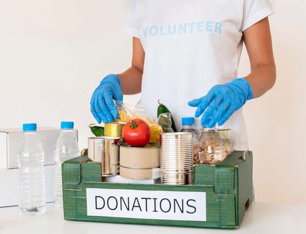 Volunteer with gloves handling box of food donations