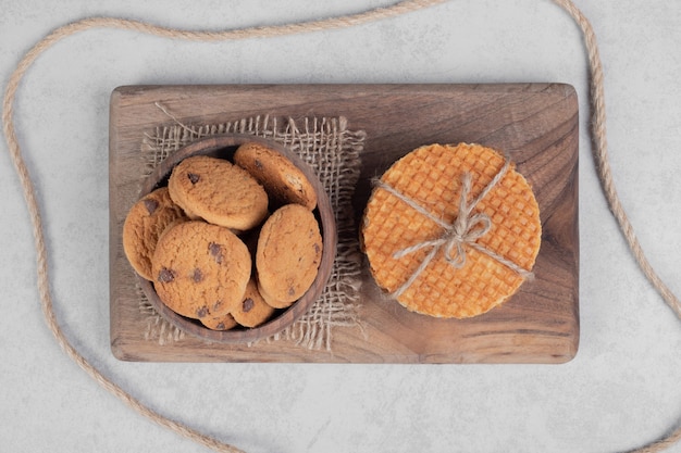 Waffle and bowl of cookies on white surface. High quality photo