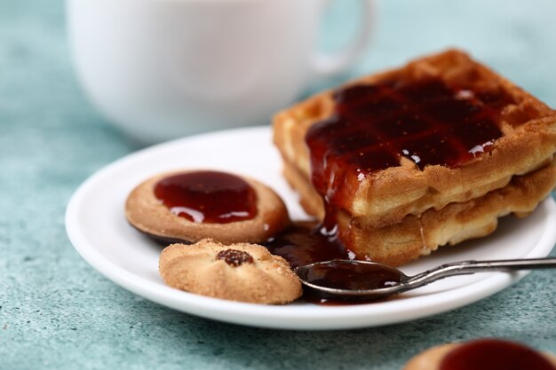 Waffle, cookies and a spoon of red jam.