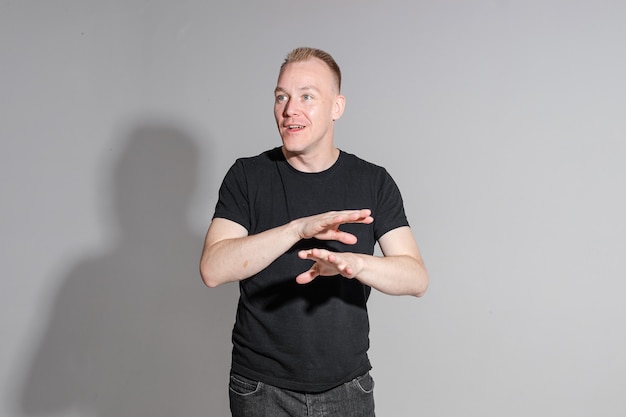 Free photo waist-up photo of expressive man in black shirt crossing his hands while posing at professional studio