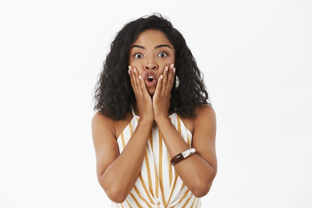 Waist-up shot of amazed girl saying lmao being excited and shocked touching face with palms folding lips