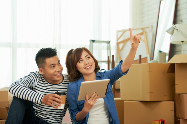 Waist up shot of couple planning interior of the room in front of packing boxes