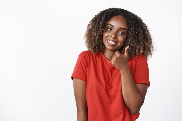 Waist-up shot of cute supportive african american womanfriend showing thumb up in like and approval tilting head and smiling broadly to cheer friend and encourage for excellent efforts over white wall