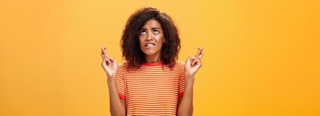 Waistup shot of hopeful concerned and anxious charming darkskinned woman with afro hairstyle in tren