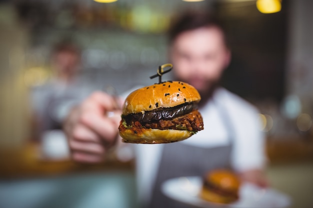 Free photo waiter holding a burger with tong