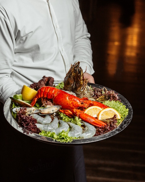 Free Photo waiter holding seafood platter with lobster king prawns and mussels