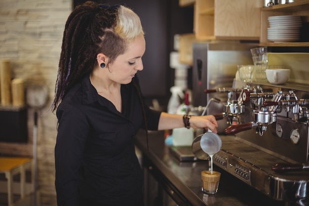 Waitress pouring milk into coffee cup at counter