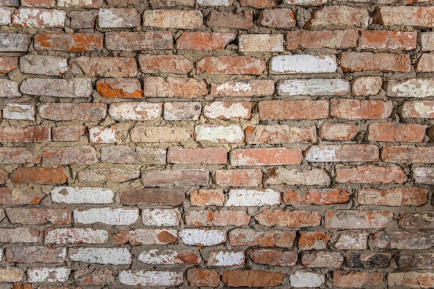 Free photo wall of an old brick building with peeled plaster and painted surface.