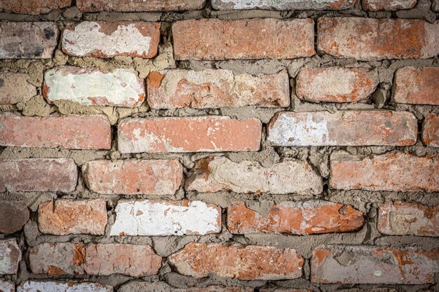 Wall of an old brick building with peeled plaster and painted texture background