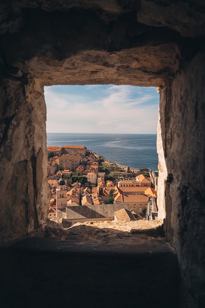 A wall opening with a view of a cityscape by the sea