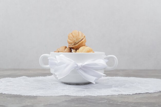 Walnut shaped cookies in white bowl.