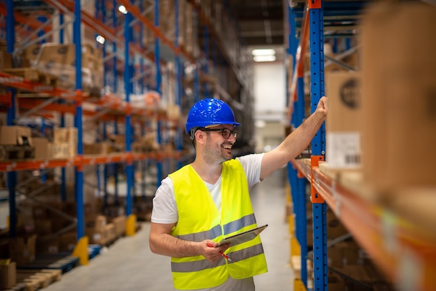 Free Photo warehouse worker looking at shelves with packages and checking inventory of large warehouse storage distribution area