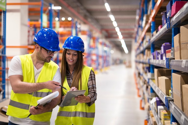 Warehouse workers checking inventory and consulting each other about organization and distribution of goods