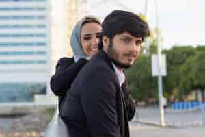 Free photo warm arabic couple spending time together. woman with covered head and bright make-up and man in suit sitting on bench. love, affection concept