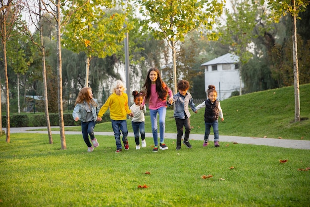 Warm. Interracial group of kids, girls and boys playing together at the park in summer day.