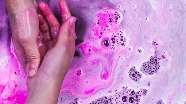 Washing hands in purple liquid with foam