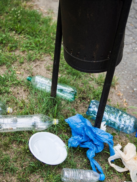 Waste plastic garbage under the black bin at park