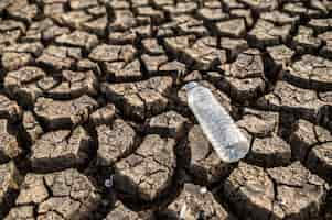 Free photo water bottles on dry soil with dry and cracked soil, global warming