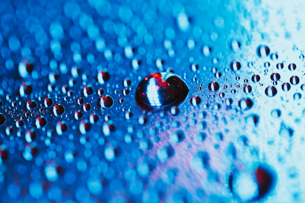 Free photo water drop on the bright blue bokeh background