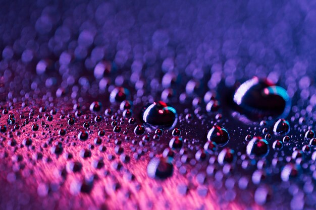 Water droplets on a blue and pink bright glass surface