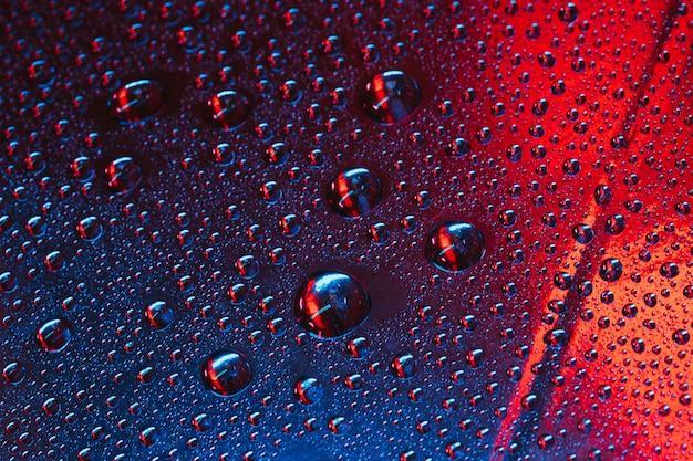 Water droplets on the glass with red and blue textured background