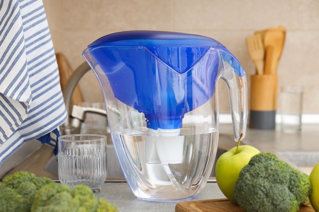 Free photo a water filter stands in the kitchen with fresh vegetables