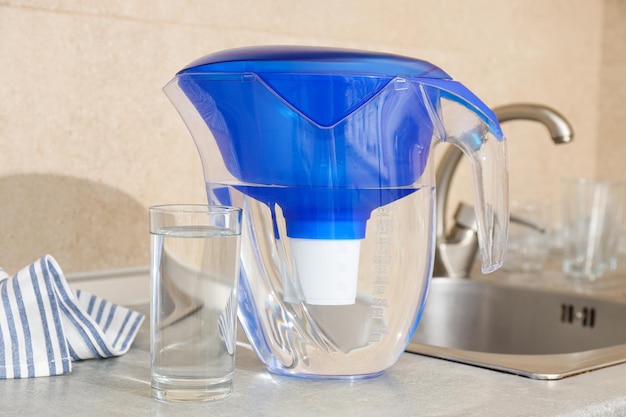 A water filter stands in the kitchen with a glass of water