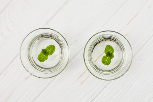 Water with mint in glasses on white table