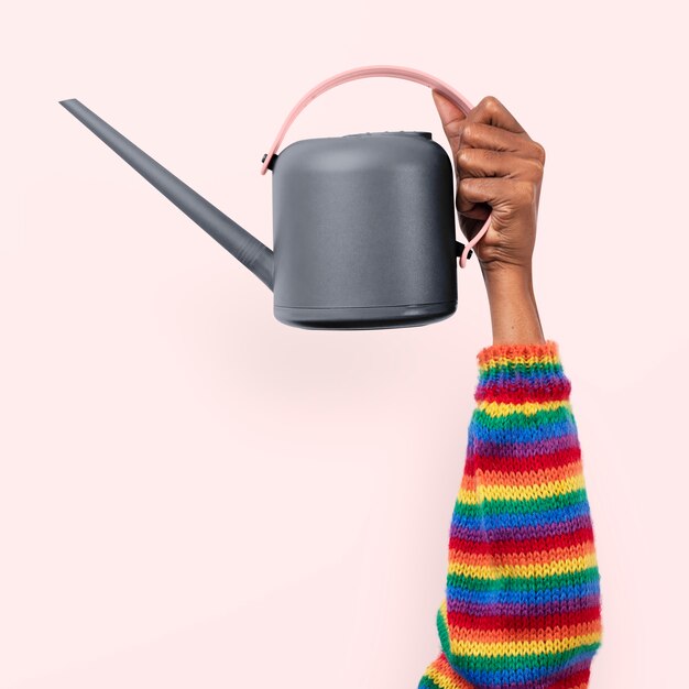 Watering can gardening tool held by a person with rainbow sleeves