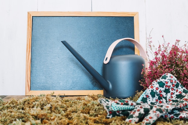 Free photo watering can and gloves near blackboard