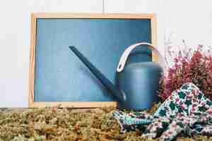 Free photo watering can and gloves near blackboard