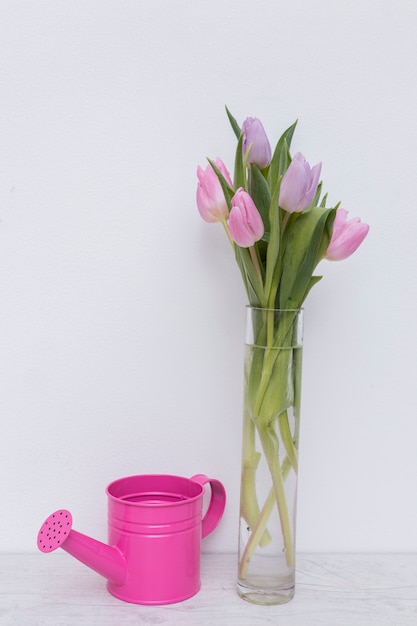 Free photo watering pot and tulips in vase